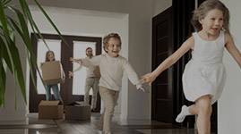 #PraCegoVer Texto: CRÉDITO IMOBILIÁRIO. Imagem: duas crianças entram correndo animadas em sua nova casa, enquanto ao fundo da imagem o pai está fechando a porta, a mãe segura uma das caixas da mudança.